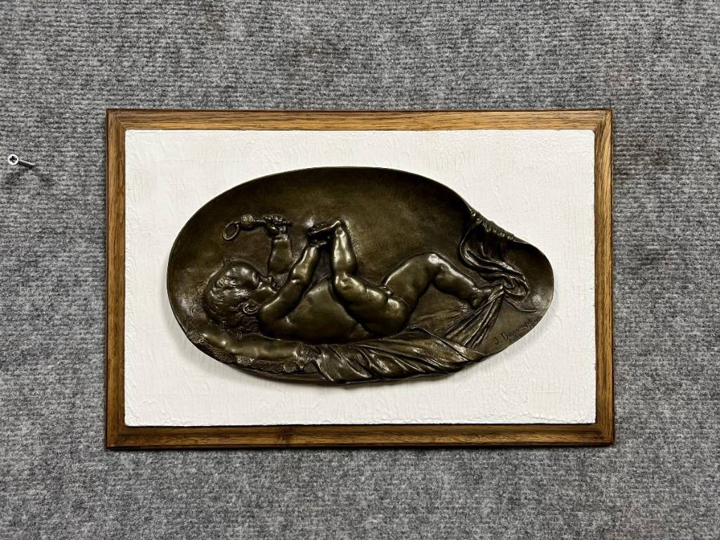 bas relief en bronze figurant un bébé jouant avec son pied et tenant un hochet dans l'autre main. | Puces Privées