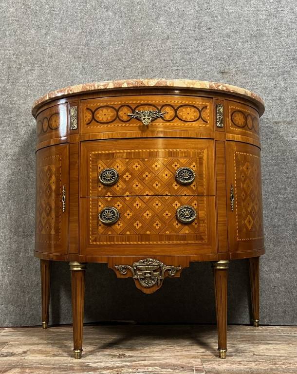 Commode demi-lune de style Louis XVI en placage de palissandre et bois de rose, marqueterie de fleurs et frisages. | Puces Privées